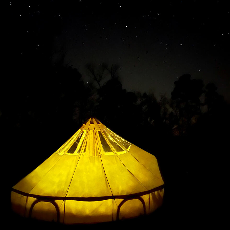 lighted bell tent under clear sky with twinkling stars